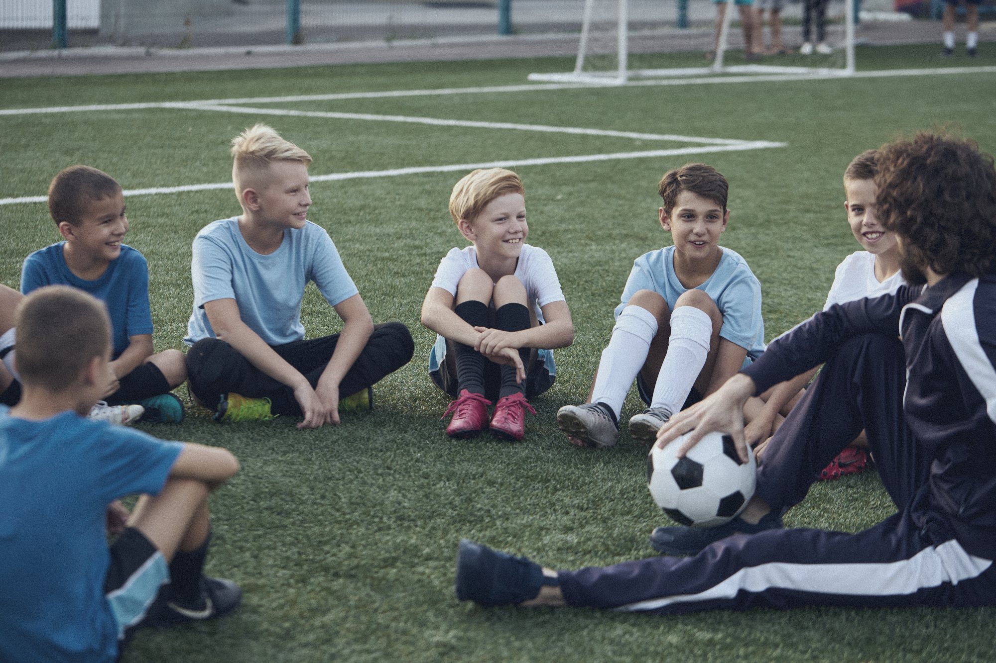 Young footballers sitting in a circle talking with their coach